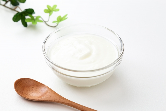 ガラスの器に盛られた白いヨーグルトと、添えられた木のスプーン