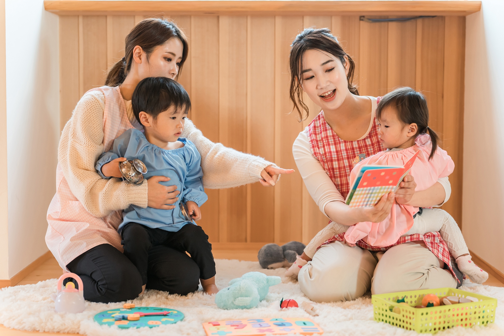 保育士2名が子ども2名に絵本を読んでいる