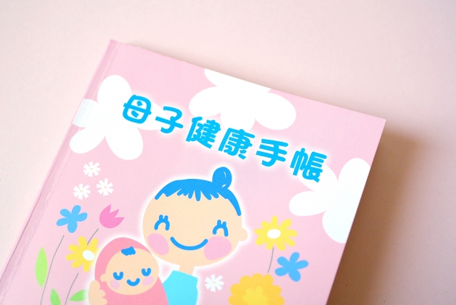ピンク色の表紙に親子のイラストが描かれた、日本の母子健康手帳