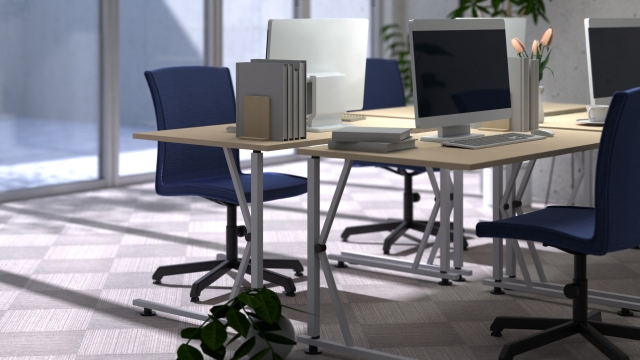 日差しが差し込む、誰もいないモダンなオフィス。パソコンが置かれた机と椅子が整然と並んでいる。
