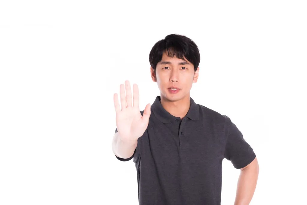 手のひらを見せて制止するポーズの男性