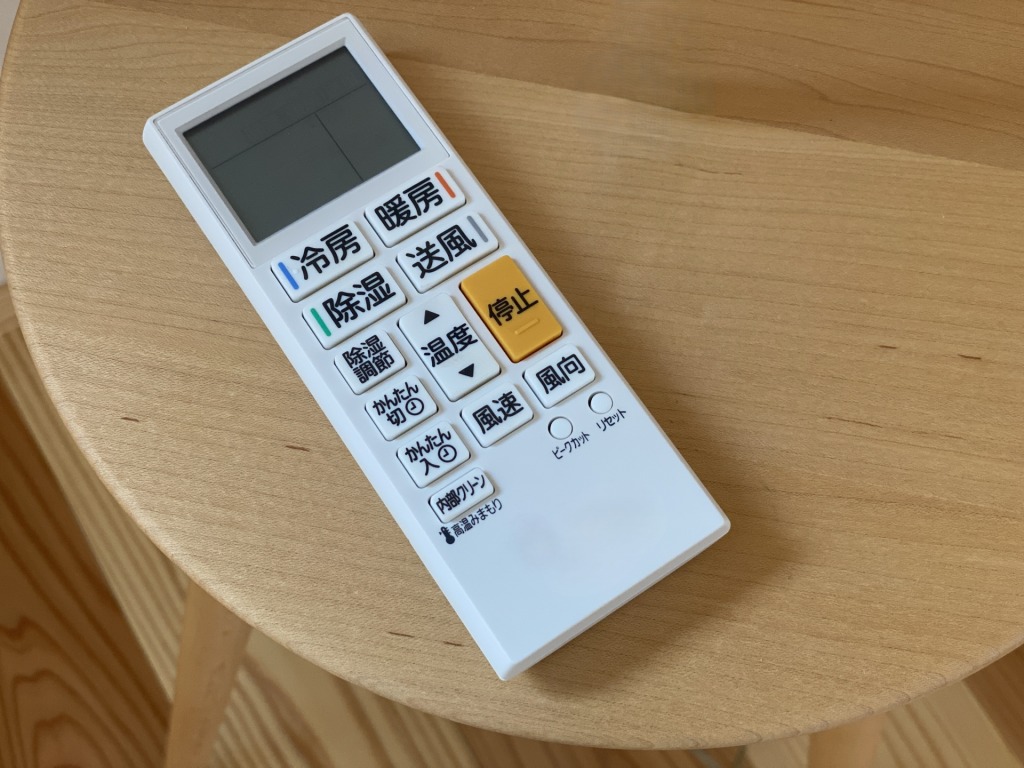 木製のテーブルに置かれたエアコンのリモコン
