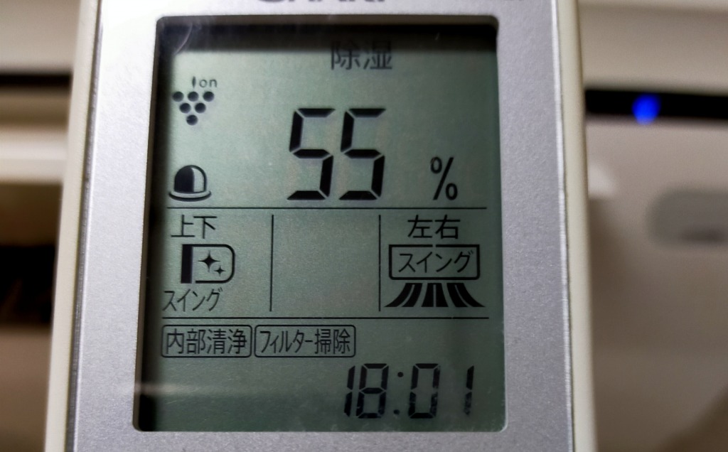 「除湿」モードと湿度「55%」、時刻「18:01」が表示されたエアコンのリモコン画面