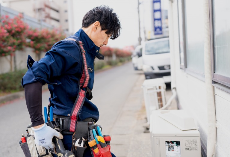 エアコンの室外機を点検する作業員